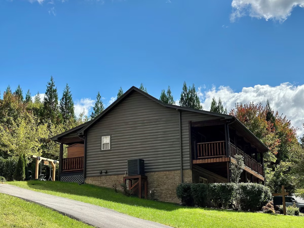 Pigeon Hills cabin side view with wraparound deck stairs and mountain forest backdrop